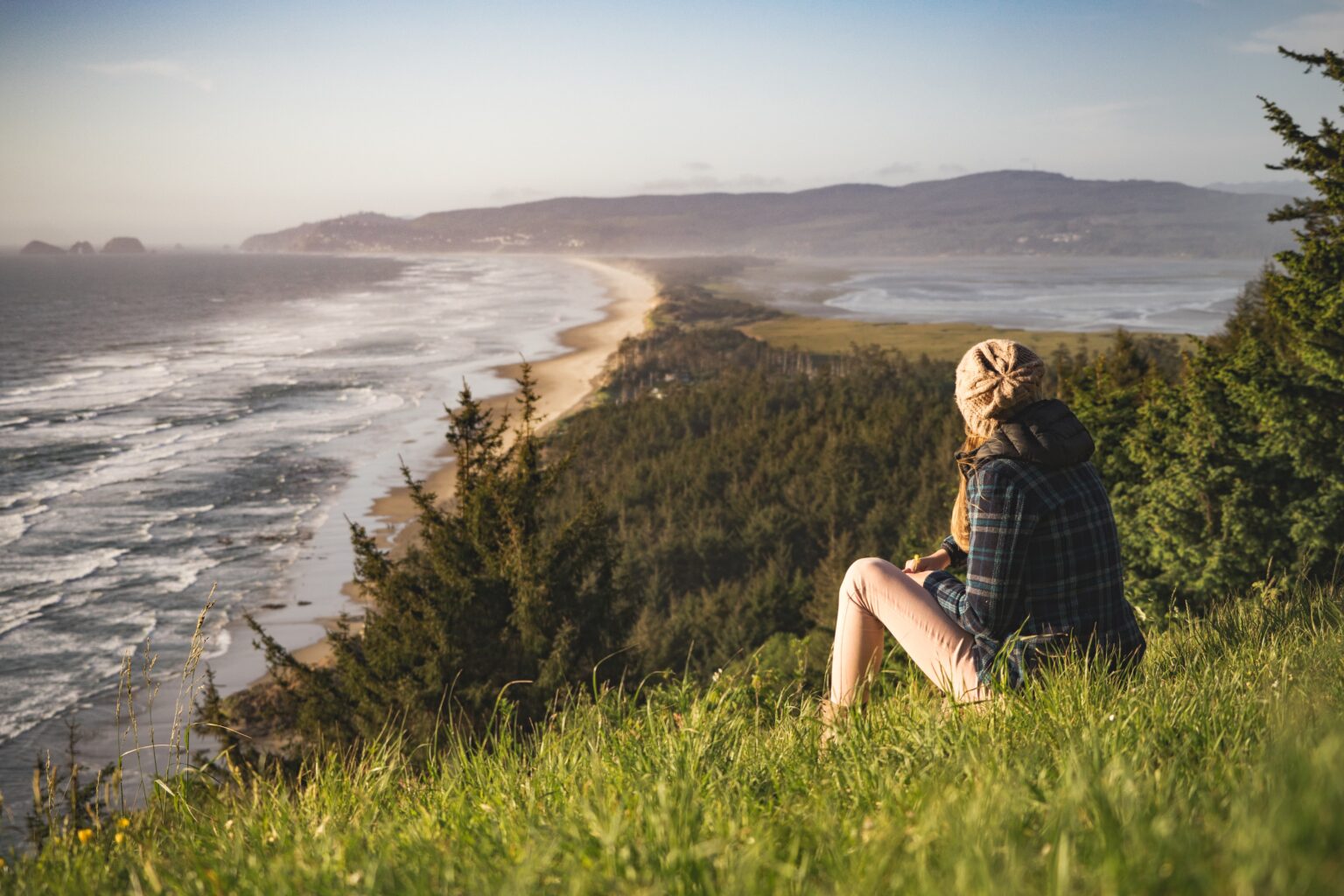 person sitting on hill near ocean during daytime